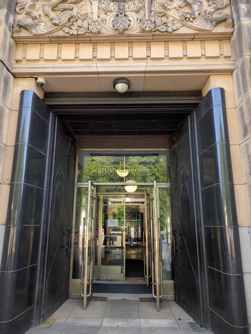 Grand entrance way to Saint Andrews House. The Scottish Government is written in gold lettering on glass doors. 
