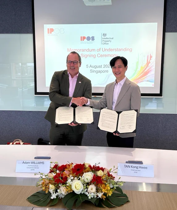 Alt text: Adam Williams IPO CEO and Tan Kong Hwee IPOS CE holding the MoU and shaking hands