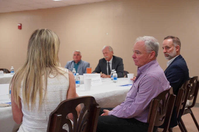 Senator Kaine sits at a table, listening to the discussion. 