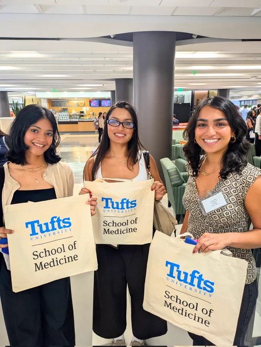 New MBS students, smiling, with tote bags.