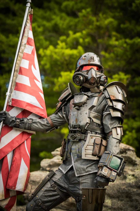 A person in a full Brotherhood of Steel Recon Armor set, holding a placed Brotherhood of Steel flag