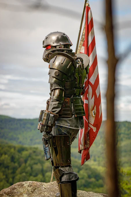 A person in a full Brotherhood of Steel Recon Armor set, holding a placed Brotherhood of Steel flag