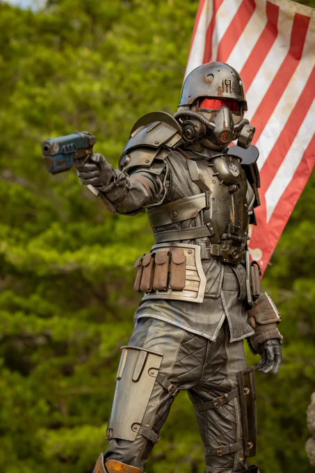 A person in a full Brotherhood of Steel Recon Armor set, holding a placed Brotherhood of Steel flag