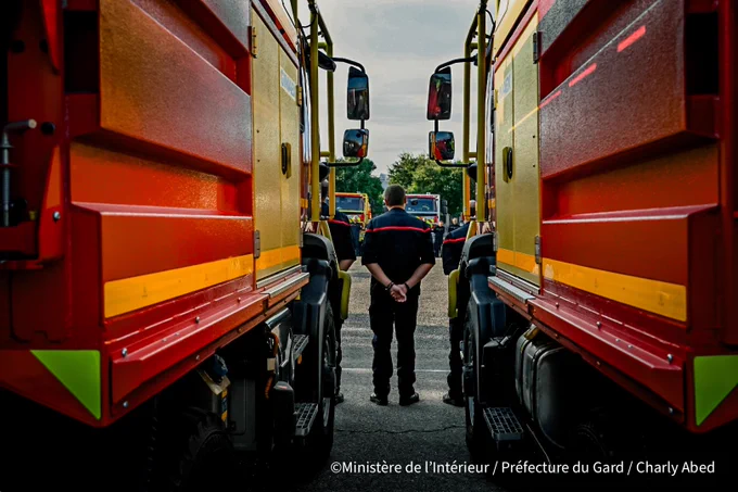 Photo d’un pompier entre deux camions de pompiers