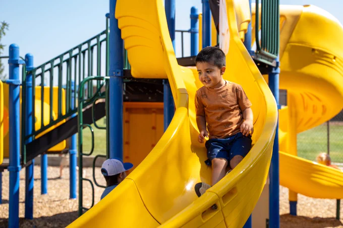 student smiles going down the slide