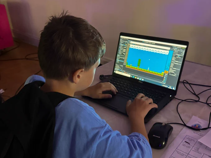 A young person playing a game on a laptop.