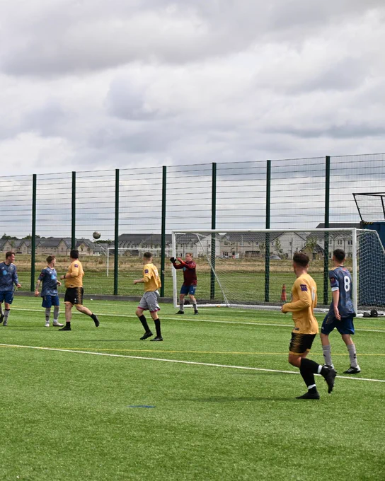 Footballers standing on the side of the pitch resting. A small girl is high-fiving one of the players.
