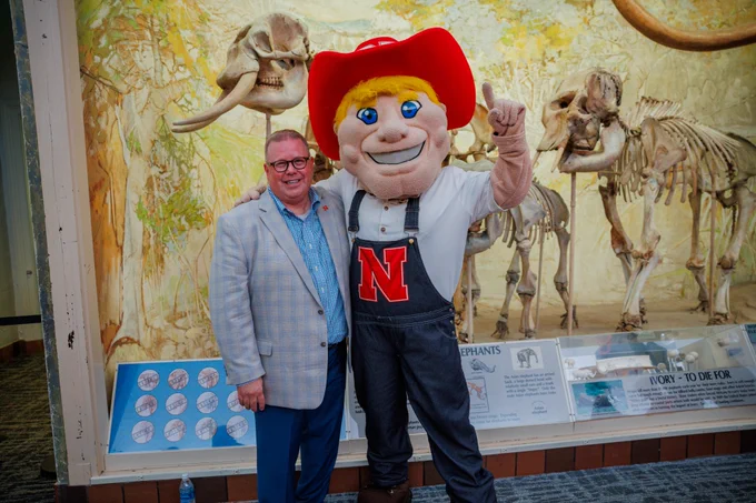 Mike Zeleny poses for a photo with Herbie Husker during his farewell reception in Morrill Hall