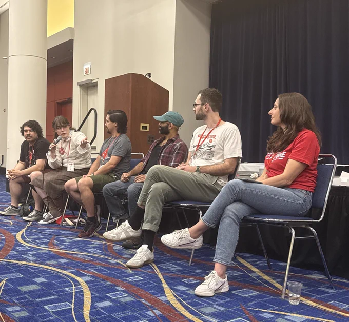 Six panelists sitting in chairs w/ Avery currently speaking