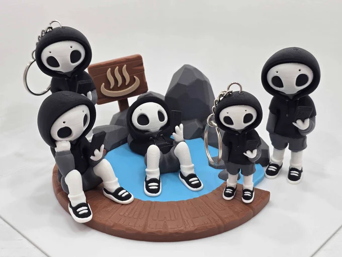 Five hooded “Project Hazy” figures, two as keychains, posed around a 3D printed hot spring scene with blue water, rocks, and a wooden sign featuring steam symbols.