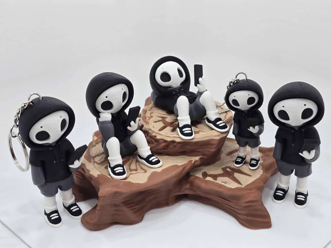  Five black-and-white hooded “Project Hazy” figures in different poses and sizes, including two keychain versions, arranged on a 3D printed layered tree stump display.