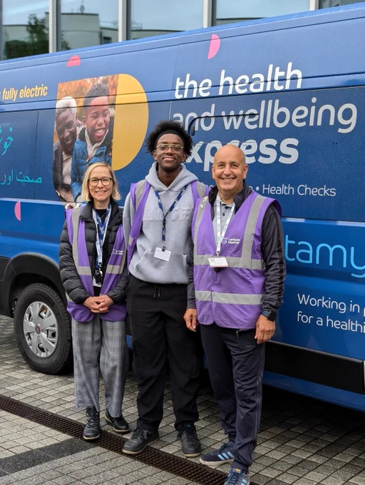 Lambeth Health and Wellbeing Champions Gail, Mo and Mem stand in front of the blue Lambeth Health and Wellbeing bus.