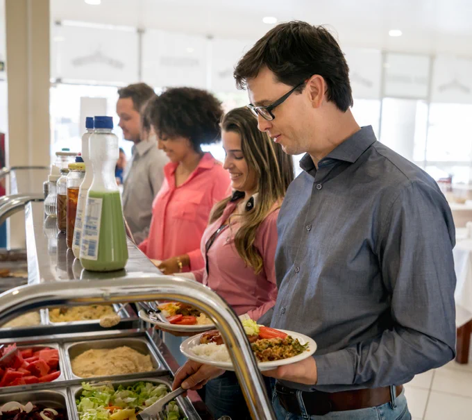 Line of people helping themselves to food at a canteen