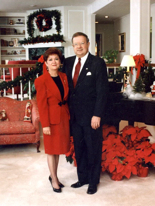 Mrs. Linda and Dr. Dan Reneau stand together near poinsettias at Christmastime.