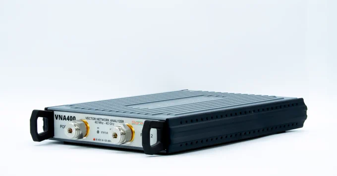 Image of a VNA400 Vector Network Analyzer by Signal Hound, featuring a sleek, gray chassis and front panel with ports labeled PO, REF, and DUT. VNA400 is inside a mounting bracket.
