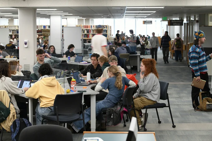 students talking at a table in howe library