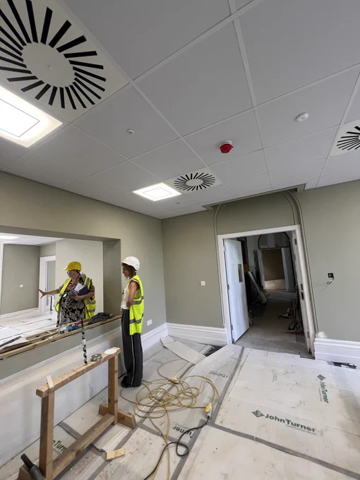 Photo of 2 workers in high vis vests inside the mansion