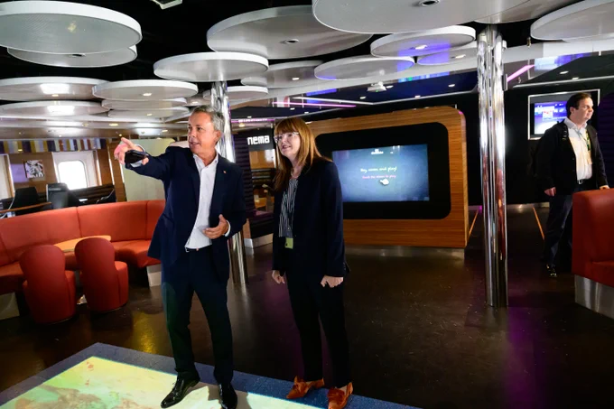 The Minister is pictured with Paul Grant in one of the lounges of the vessel, that includes an light up image on the floor at their feet.