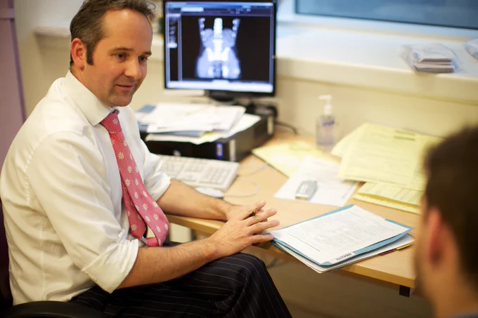 A clinician, who is the subject of the photograph, talks to a patient.