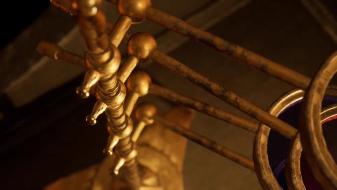 Close-up view of a brass device with several horizontal rods ending in spherical knobs, shown at a dramatic angle and in warm lighting. The rods appear slightly tarnished and weathered.