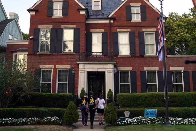 Three people walk up to John Block's brick Shadyside mansion at dusk on Tuesday, Aug. 12 during a Pittsburgh Post-Gazette strike rally.