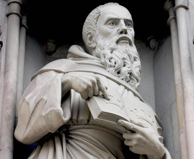 Close-up of a statue of St Maximilian Kolbe, showing him with a long beard, wearing robes and holding a book