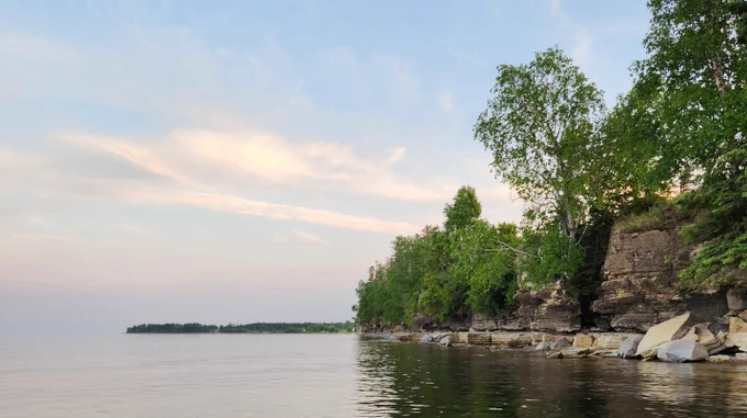 Water, trees and rocks under a blue sky