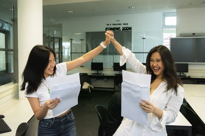 Two girls at Skinners Academy cheering and holding their results