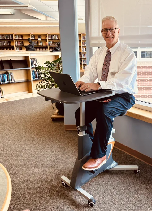 “Testing out the new ride in one of our middle school libraries—pedaling through emails and chapters at the same time!”