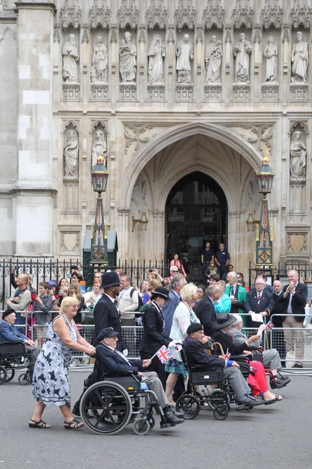 A group of veterans in wheelchairs being pushed past Westminster Abbey during a parade to mark the 70th anniversary of VJ Day in 2015