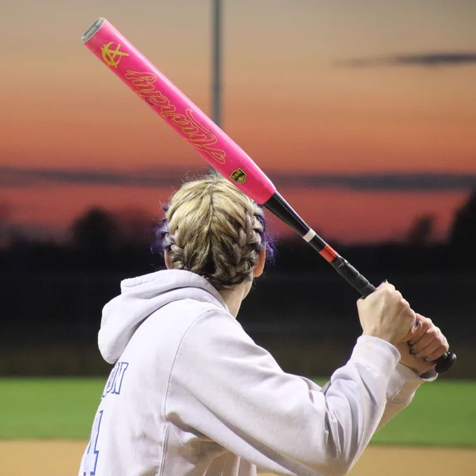 A girl holds up her bat, ready to swing ta the ball.