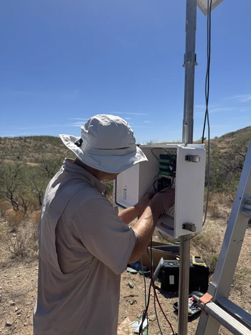 USGS scientist B. Smith is connecting wires inside the electrical housing on the evapotranspiration tower. 