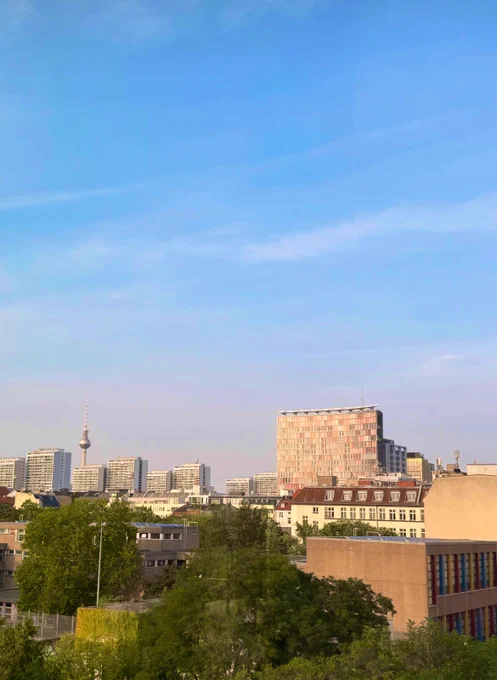 Berlin von Kreuzberg aus gesehen: das ikonische GSW-Hochhaus mit den rot-magenta-farbenen Fensterläden des Büro Sauerbruch Hutton, die Hochhäuser der Leipziger Straße, Modell dichten Wohnens in der Innenstadt, der Fernsehturm am Alexanderplatz. Bildung, Wohnen, Alltag, Kultur, Städtebau, Naherholung, Lifestyle, Tourismus, Freiheit: lokal - global. Offene Gesellschaft, offene Zukunft.

Headline geliehen einer Publikation zur Bildung und Gemeinschaft der Zukunft. Darin u.a. Bundesverfassungsgericht-Richterin Lore Peschel-Gutzeit.