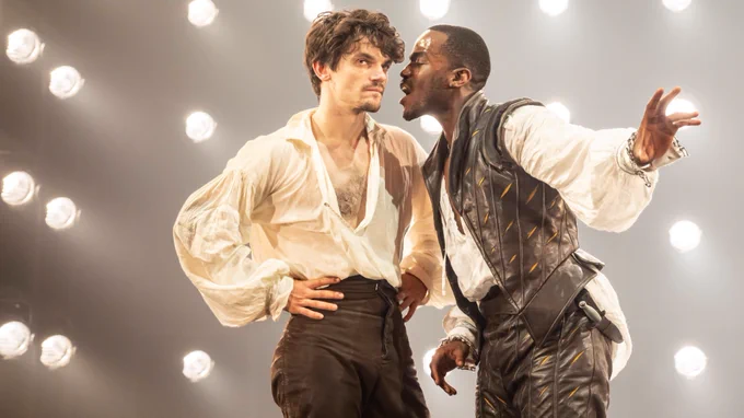 Ncuti Gatwa leaning his face towards Edward Bluemel's face. Both are dressed in Elizabethan costumes