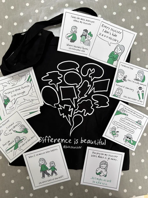 Photograph of several of Willemijn Bolks @JustStutter cards positioned on a black tote bag  featuring different shaped speech bubbles in white & the writing ‘Difference is beautiful’