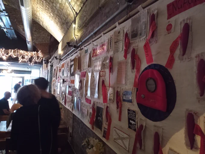 The Peterloo tapestry, a long stretch of cloth covered with items created by the public to commemorate the Peterloo massacre, with a red woollen Liberty cap in the foreground