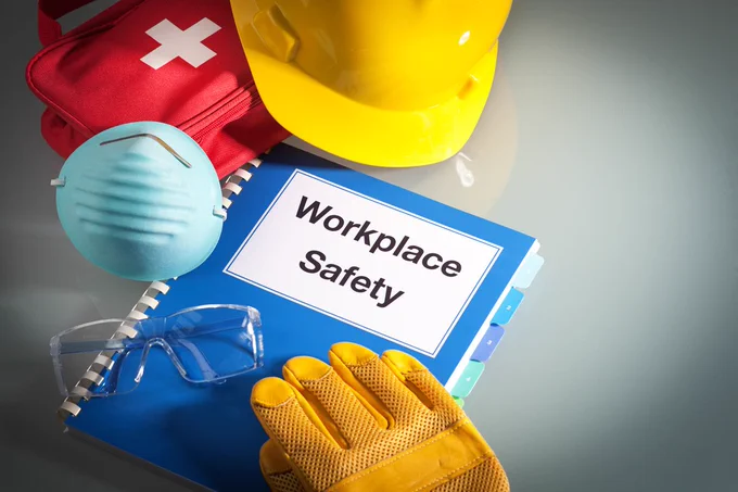 Work safety manual with glasses, gloves, hard hat and a first aid kit.