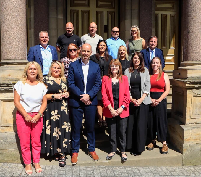 Minister for the Economy Caoimhe Archibald with members of the North-West Community Wealth Building Partnership at St. Columb's Hall.