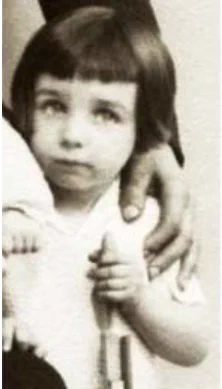 Close-up of a vintage black-and-white photo showing a young boy with shoulder-length hair and bangs, looking upward with a thoughtful expression.

