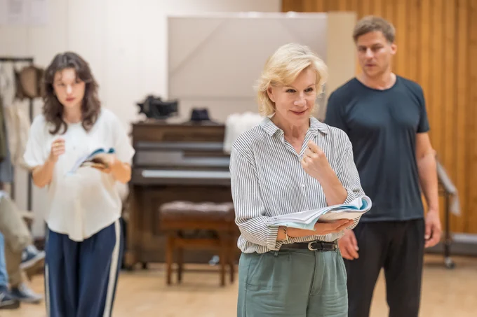 A photo showing three performers in casual attire in a generic rehearsal room space 