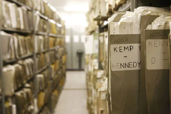 A view of the shelving at BBC Written Archives Centre. A file pokes out labelled "Kemp - Kennedy".