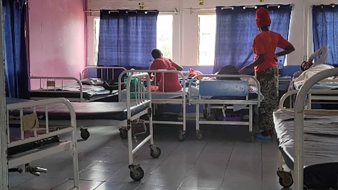 A maternity ward with two women seated on the bed.