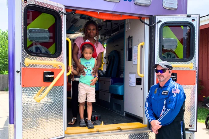 Child and adult in an ambulance while worker stands by