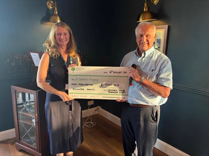 A lady wearing a St Teresa's Hospice lanyard holding a cheque for £1, 000 with a gentleman from Teesside West Rotary Club.