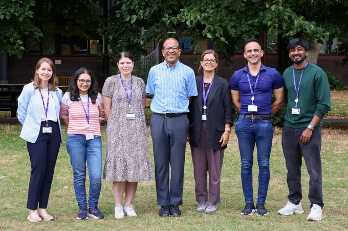 Seven members of the PCRF tissue bank team stand on a grassy green, smiling at the viewer
