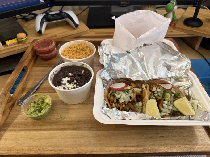 Plate of two al pastor tacos, rice, beans, chips, salsa, and guac.