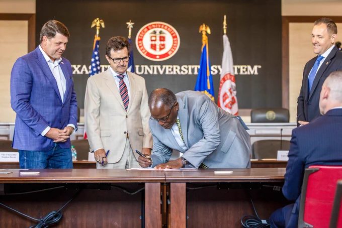 One individual signing a paper as others look on. 