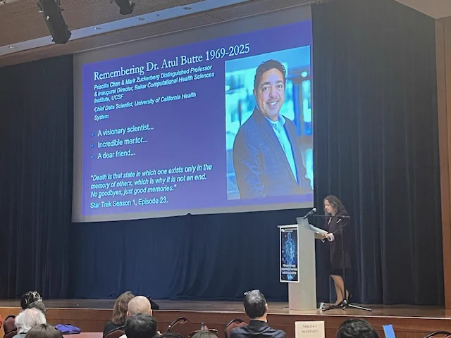 Marina Sirota sharing a slide about Atul's life.
