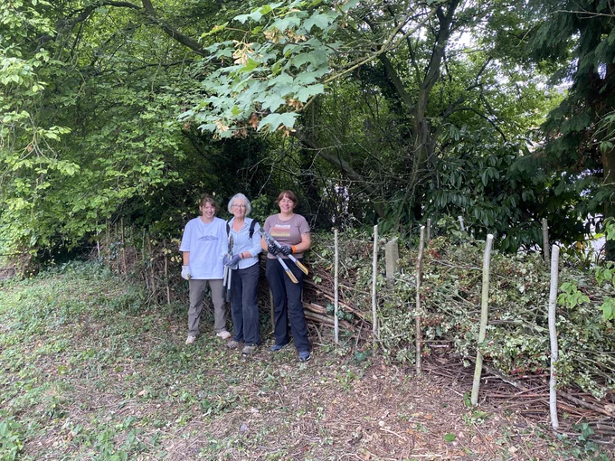 Three of the volunteers having repaired and topped up a dead hedge that had been previously damaged by trampling. New coppiced stakes were added and topped up with saved tree prunings cut back by the CountrysideNK Ranger along the Eastgate Road footpath earlier on in the week.