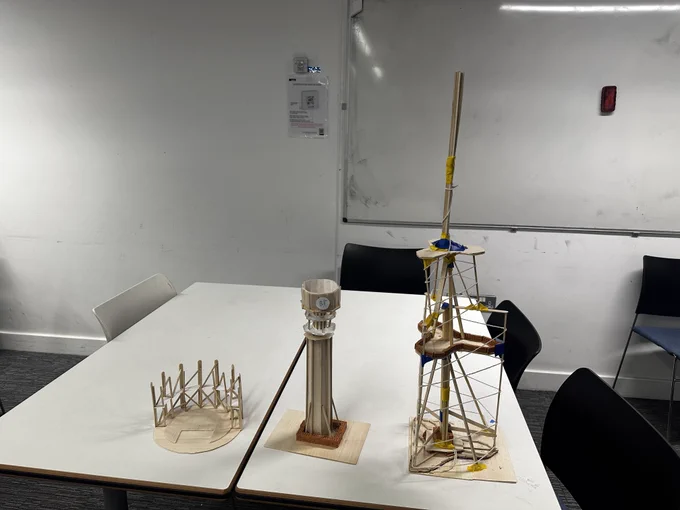 Image of a classroom with two tables displaying student construction projects including the Globe theatre, BT Tower, and the Burj Khalifa.